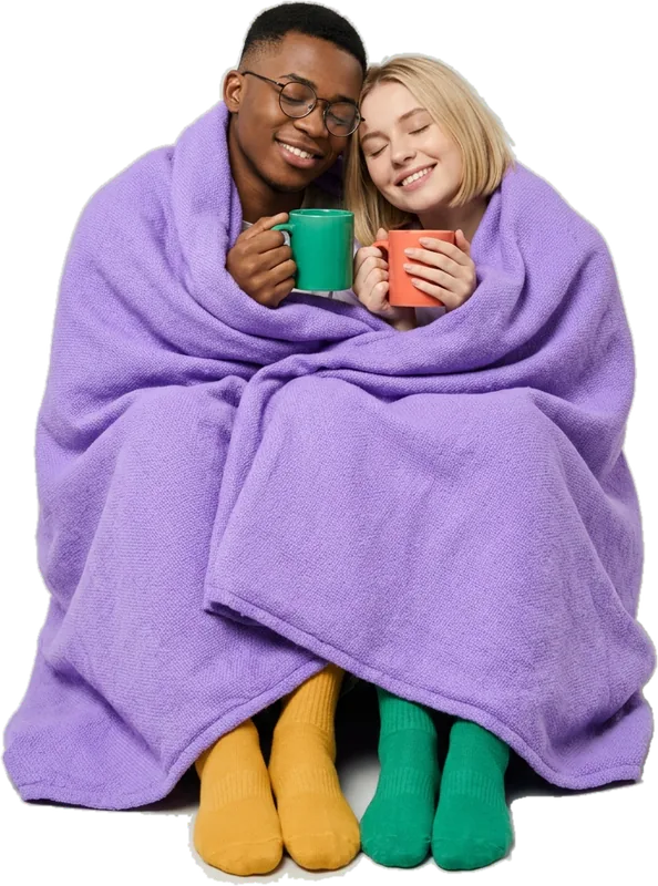 Couple wrapped together in one purple blanket, holding mugs